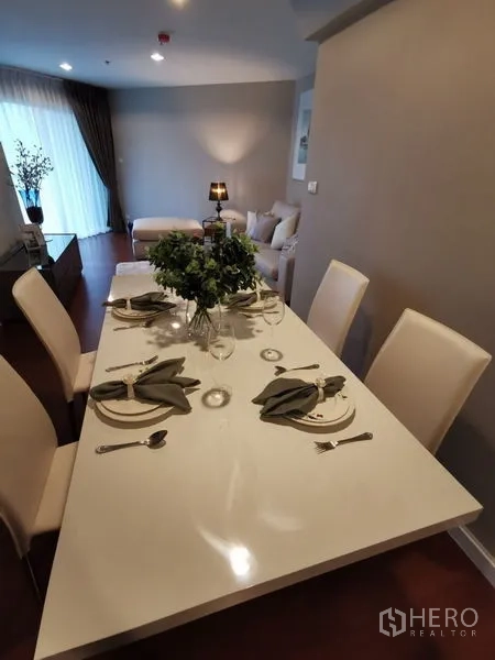 Condominium for rent or sale in Huai Khwang, Bangkok - Open-plan dining set laid for four overlooking the living area with a sofa.