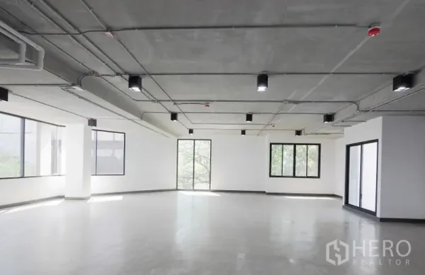 Office Space for rent in Watthana, Bangkok - Corner office floor featuring wraparound windows, smooth concrete flooring, and modern ceiling fixtures with abundant natural light.
