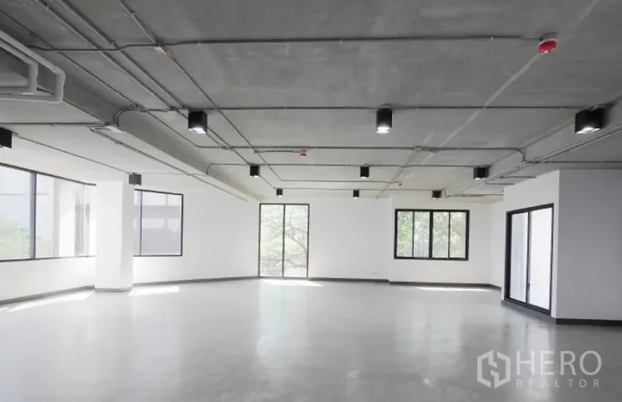 Office Space for rent in Watthana, Bangkok - Corner office floor featuring wraparound windows, smooth concrete flooring, and modern ceiling fixtures with abundant natural light.