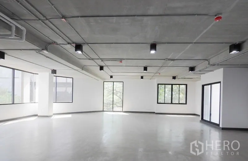 Office Space for rent in Watthana, Bangkok - Corner office floor featuring wraparound windows, smooth concrete flooring, and modern ceiling fixtures with abundant natural light.