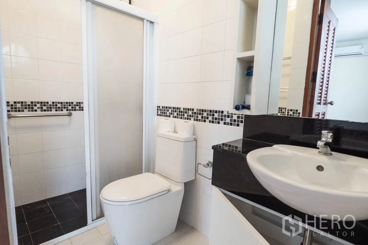 Townhouse for rent in Watthana, Bangkok - Modern bathroom with sliding shower enclosure, vanity, and toilet.