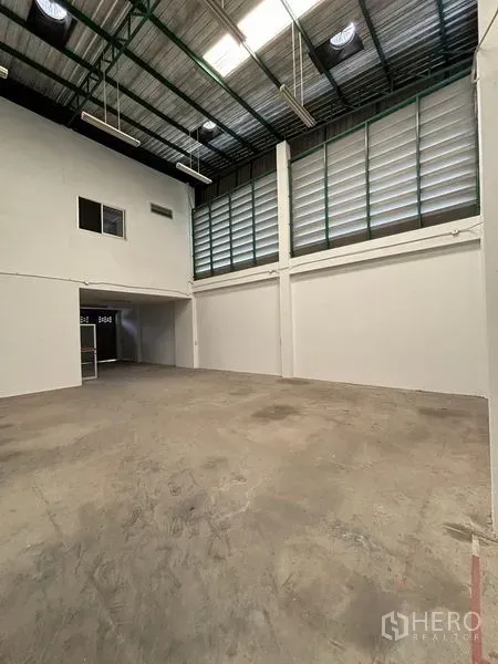 Warehouse for rent in Phra Samut Chedi, Samut Prakan - Spacious warehouse interior with high steel roof, louvered windows, skylights and concrete floor.