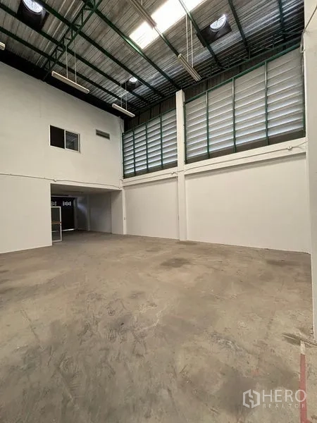 Warehouse for rent in Phra Samut Chedi, Samut Prakan - Spacious warehouse interior with high steel roof, louvered windows, skylights and concrete floor.