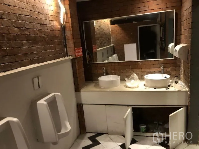 อาคารพาณิชย์ ให้เช่าในWatthana, Bangkok - ห้องน้ำผนังอิฐ กระจกบานใหญ่ อ่างล้างหน้าคู่ และโถปัสสาวะ