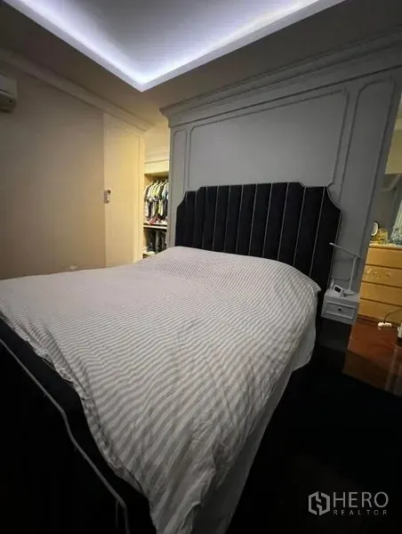 Townhouse for rent or sale in Bueng Kum, Bangkok - Cozy bedroom with upholstered headboard and access to a walk-in closet.