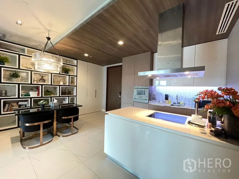 Condominium for rent in Pathum Wan, Bangkok - Contemporary kitchen with island, chandelier dining area and display shelving.