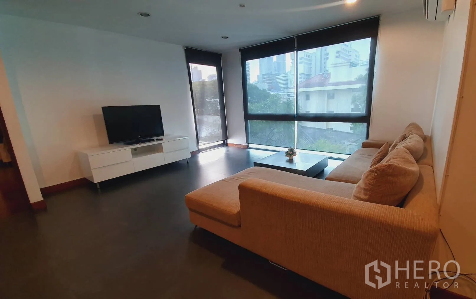 คอนโด ให้เช่าในKhlong Toei, Bangkok - ห้องนั่งเล่นมีโซฟาเข้ามุม ทีวี และหน้าต่างกระจกเต็มบานมุมห้องเห็นวิวเมือง