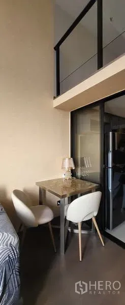 Condominium for rent - Two-seat dining nook beneath a mezzanine next to a glass-partitioned area.