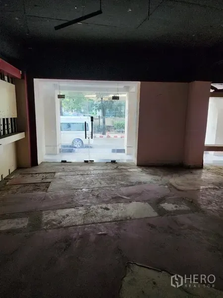 พื้นที่ขายปลีก ให้เช่าในKhlong Toei, Bangkok - ภายในร้านเปล่ามองออกสู่ประตูกระจกหน้าร้าน พื้นคอนกรีตและฝ้าเพดานสีเข้ม
