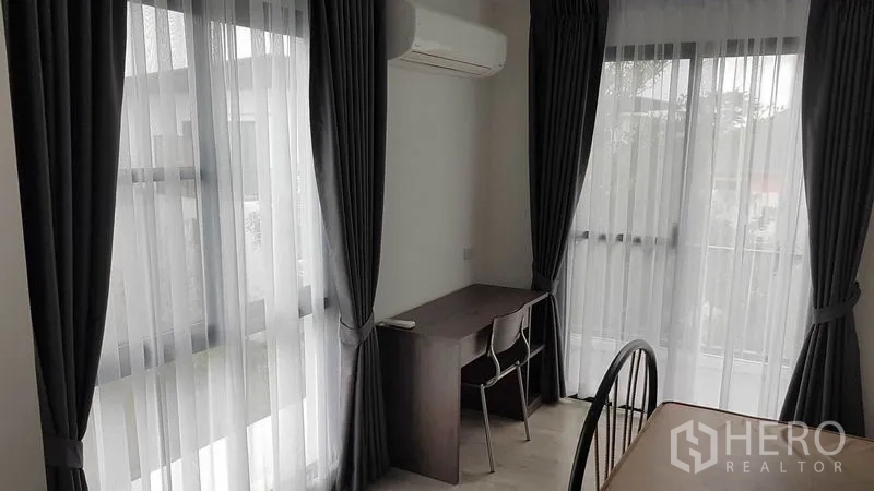 Detached House for rent in Prawet, Bangkok - Corner study area with desk and two windows dressed with curtains.