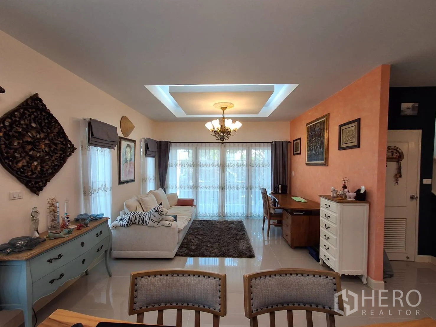 Detached House for rent or sale in Ban Chang, Rayong - Open-plan sitting area with sofa, desk and tray ceiling lighting.