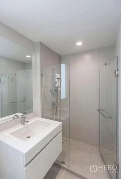 独立式住宅 出租或出售在Lat Phrao, Bangkok - 现代卫浴，玻璃淋浴房、白色洗手台与浅色瓷砖。