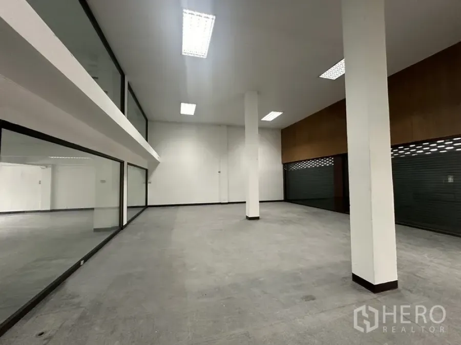 Office Space for rent in Khlong Toei, Bangkok - Spacious double-height office area with white columns, glass partitions and fluorescent lighting.
