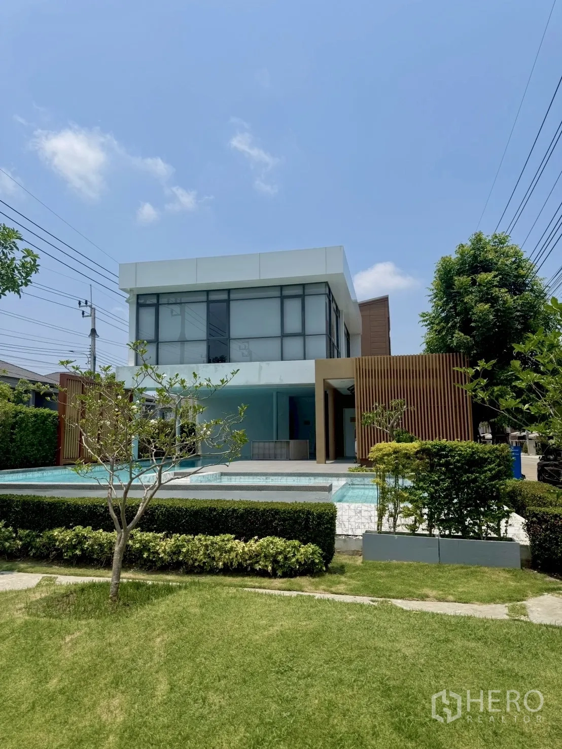 联排别墅 for rent in Prawet, Bangkok - 现代会所外观与室外泳池及草坪。