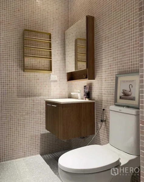 Condominium for rent or sale in Watthana, Bangkok - Mosaic-tiled bathroom with floating wooden vanity, mirror cabinet and toilet.