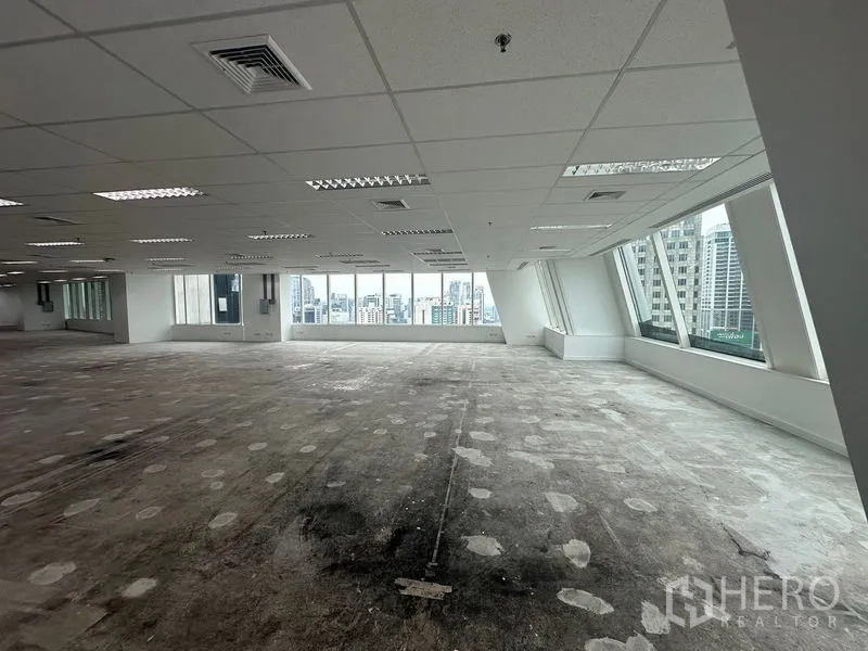 Office Space for rent - Open office with AC ducts, white columns and glazing along both sides.