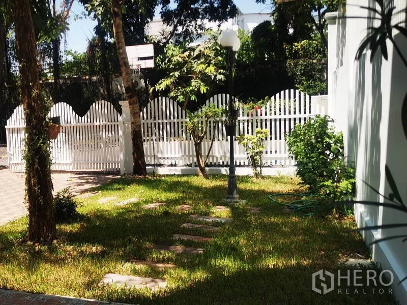 独立式住宅 出租在Mueang Samut Prakan, Samut Prakan - 阳光草坪，石板步道、路灯与白色栅栏