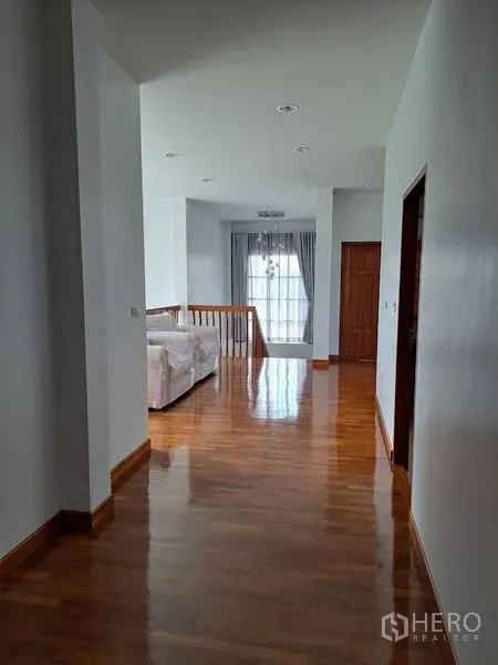 Detached House for rent in Prawet, Bangkok - Upper hallway with polished wood floors leading to a sitting area and balcony-style window.