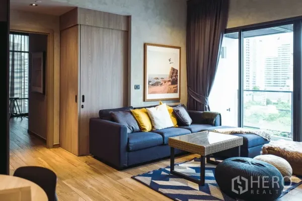 คอนโด ให้เช่าหรือขายในWatthana, Bangkok - ห้องนั่งเล่นสว่างด้วยพื้นไม้ โซฟาสีน้ำเงิน และระเบียงวิวเมือง