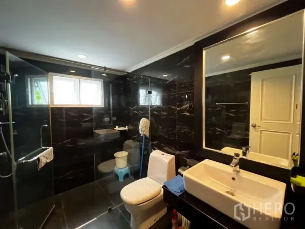 บ้าน ให้เช่าในPrawet, Bangkok - ห้องน้ำโมเดิร์นกรุหินอ่อนสีดำ พร้อมตู้กระจกอาบน้ำและเคาน์เตอร์อ่างล้างหน้า.