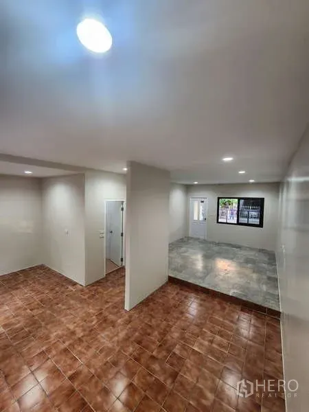 Townhouse for rent in Wang Thonglang, Bangkok - Open-plan living area with split-level tiled floors and recessed lights.