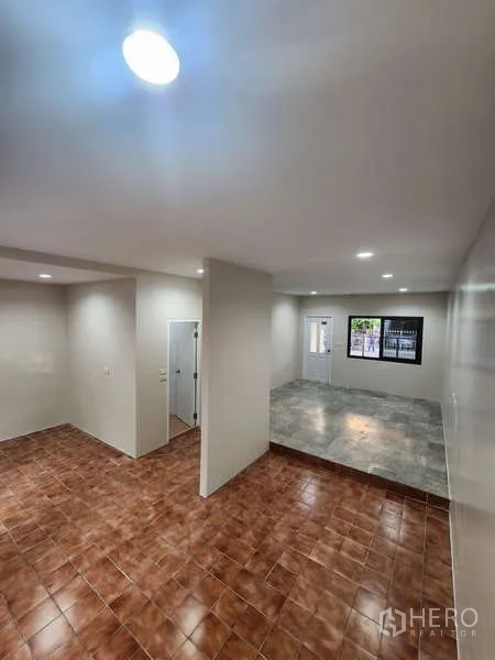 Townhouse for rent in Wang Thonglang, Bangkok - Open-plan living area with split-level tiled floors and recessed lights.