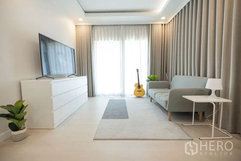 Detached House for rent or sale in Bang Phli, Samut Prakan - Main living room with sofa, TV console, sliding glass doors and floor-to-ceiling curtains.