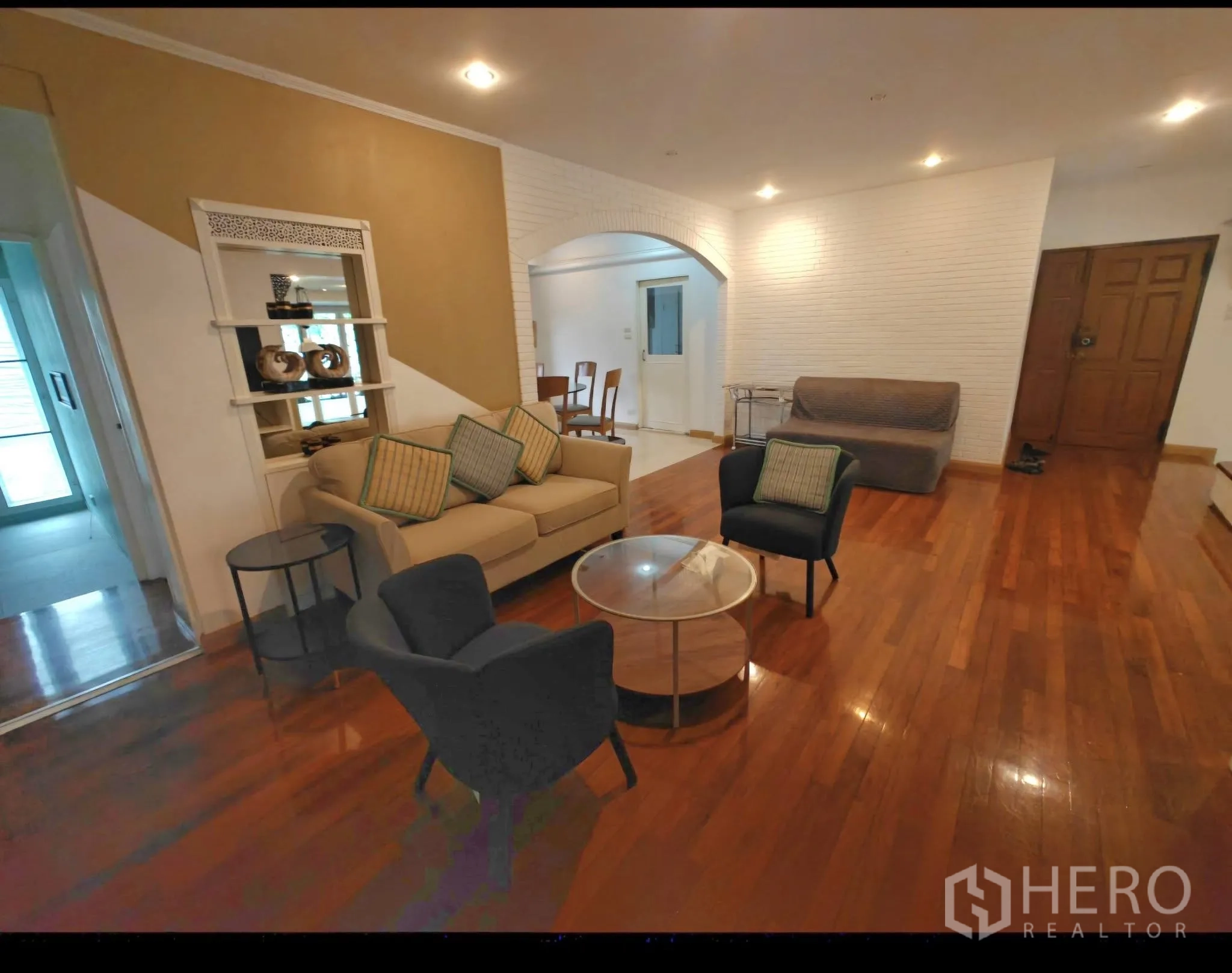 Condominium for rent in Sathon, Bangkok - Spacious entry living area with hardwood floors, sofa set, recessed lighting, and arched niche.