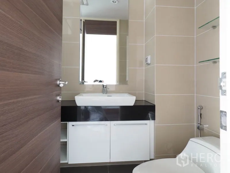 Condominium for rent or sale in Yan Nawa, Bangkok - Guest bathroom with modern vanity, mirror and beige wall tiles.