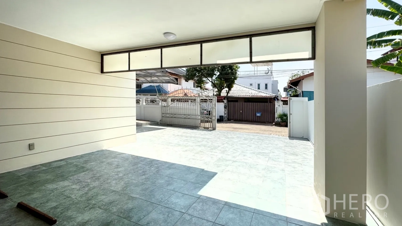 独栋房屋 for rent in Suan Luang, Bangkok - 带顶停车位向外望去，可见金属滑门与宽敞的铺砖庭院。