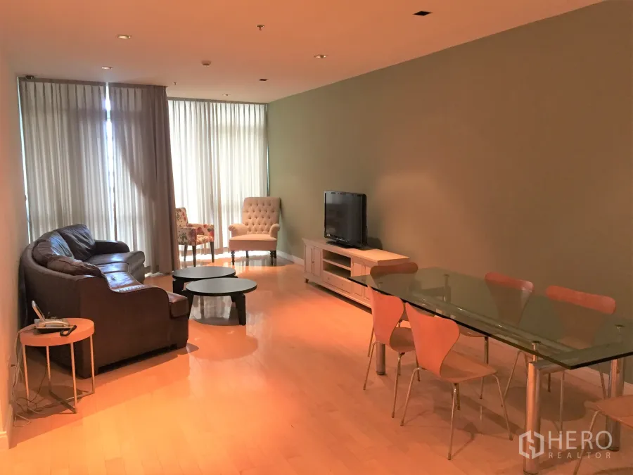 Condominium for rent or sale in Pathum Wan, Bangkok - Spacious living and dining room with leather sofa, glass table, TV console and floor-to-ceiling curtains on light wood flooring.