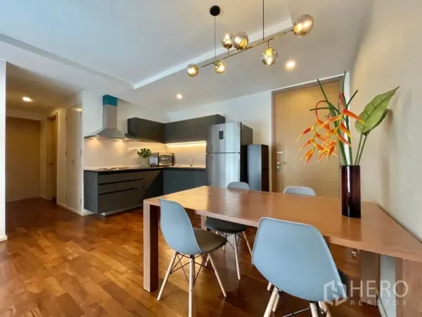 คอนโด ให้เช่าหรือขายในKhlong Toei, Bangkok - โต๊ะทานอาหารสี่ที่นั่งใต้โคมไฟแขวน ข้างครัวสีเทาทันสมัย