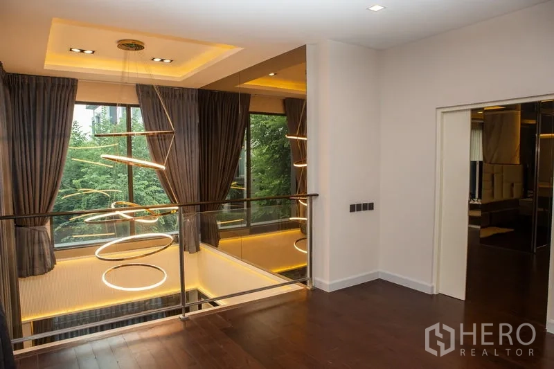 独立式住宅 出租或出售在Bangkok - 二层过道眺望挑空与造型吊灯，落地窗采光。