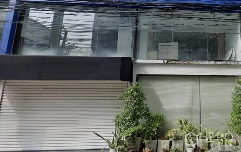 พื้นที่ขายปลีก ให้เช่าในWatthana, Bangkok - อาคารหน้ากระจกสองชั้น พร้อมประตูม้วนและกระถางต้นไม้ ในเขตวัฒนา