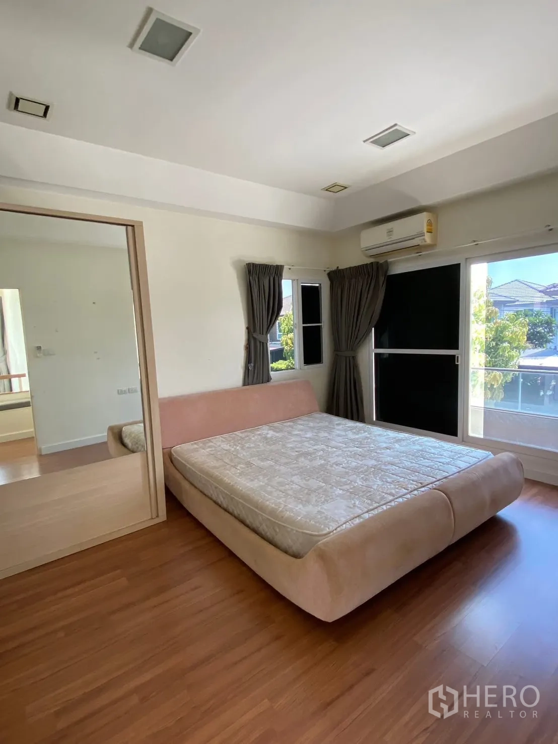 Detached House for rent in Prawet, Bangkok - Bright bedroom with platform bed, wood floors, mirrored wardrobe, and air conditioner.