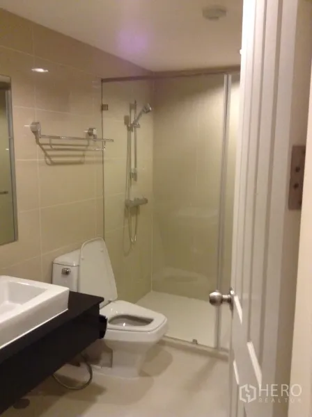 Condominium for rent in Huai Khwang, Bangkok - Modern bathroom featuring a glass-enclosed shower, vanity and toilet.