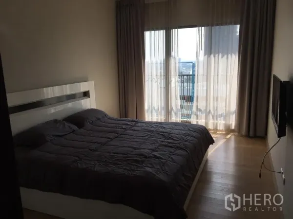 คอนโด ให้เช่าในBangkok - ห้องนอนอบอุ่น มีหน้าต่างขนาดใหญ่ ผ้าม่านทึบ ระเบียงเห็นวิวเมือง และพื้นไม้