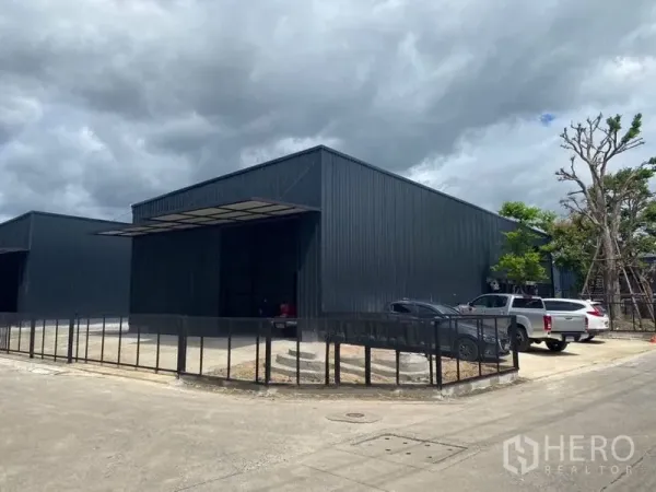 คลังสินค้า ให้เช่าในLat Phrao, Bangkok - โกดังเมทัลชีทสีดำสมัยใหม่ในลาดพร้าว กรุงเทพฯ มีที่จอดรถและรั้วล้อม บรรยากาศท้องฟ้าครึ้ม.