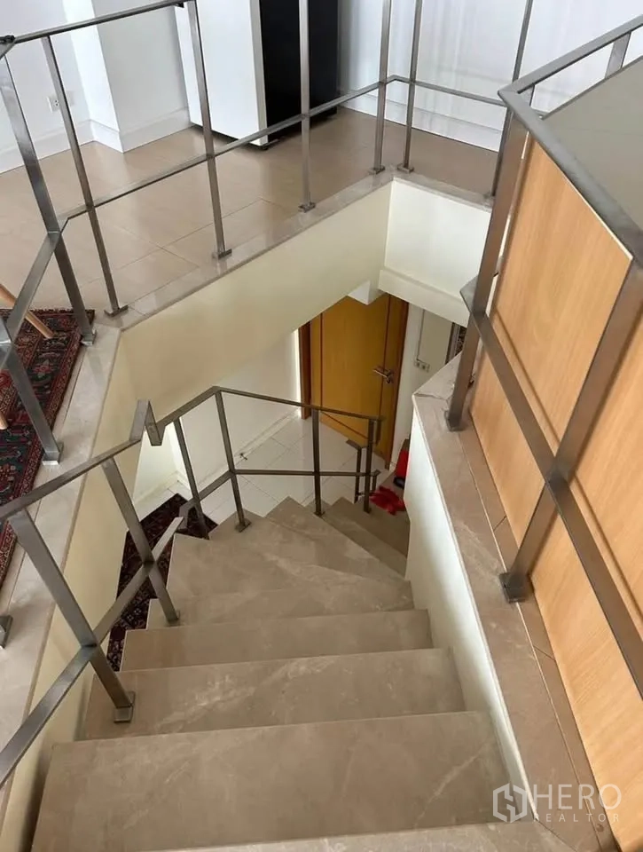 Condominium for rent or sale in Yan Nawa, Bangkok - Interior staircase with metal railing connecting the duplex levels.