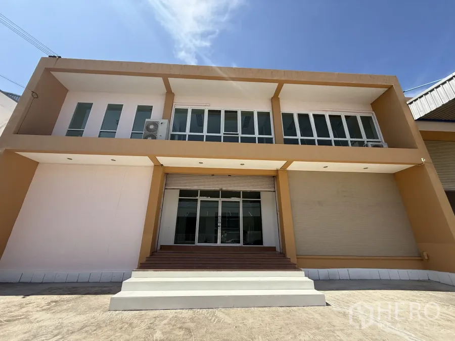 Warehouse for rent or sale in Bang Bo, Samut Prakan - Front facade of the office block with wide steps, glass entry and a roller shutter door.