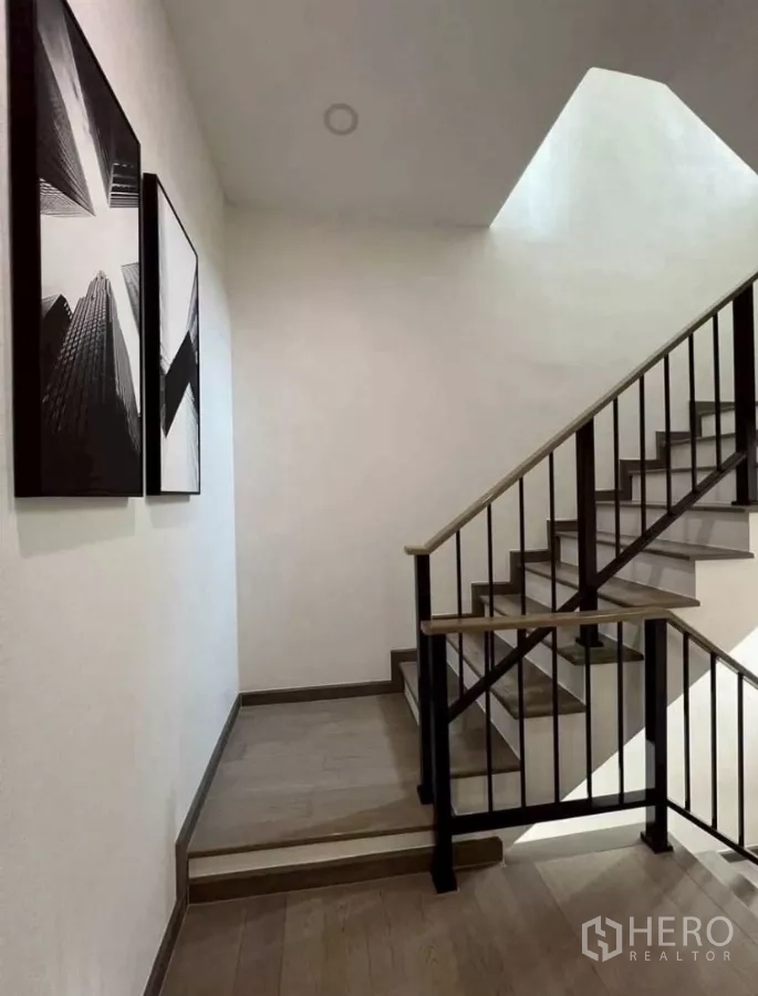 独立式住宅 出租在Lat Phrao, Bangkok - 楼梯间配黑色金属栏杆与木踏步，上方有天窗。