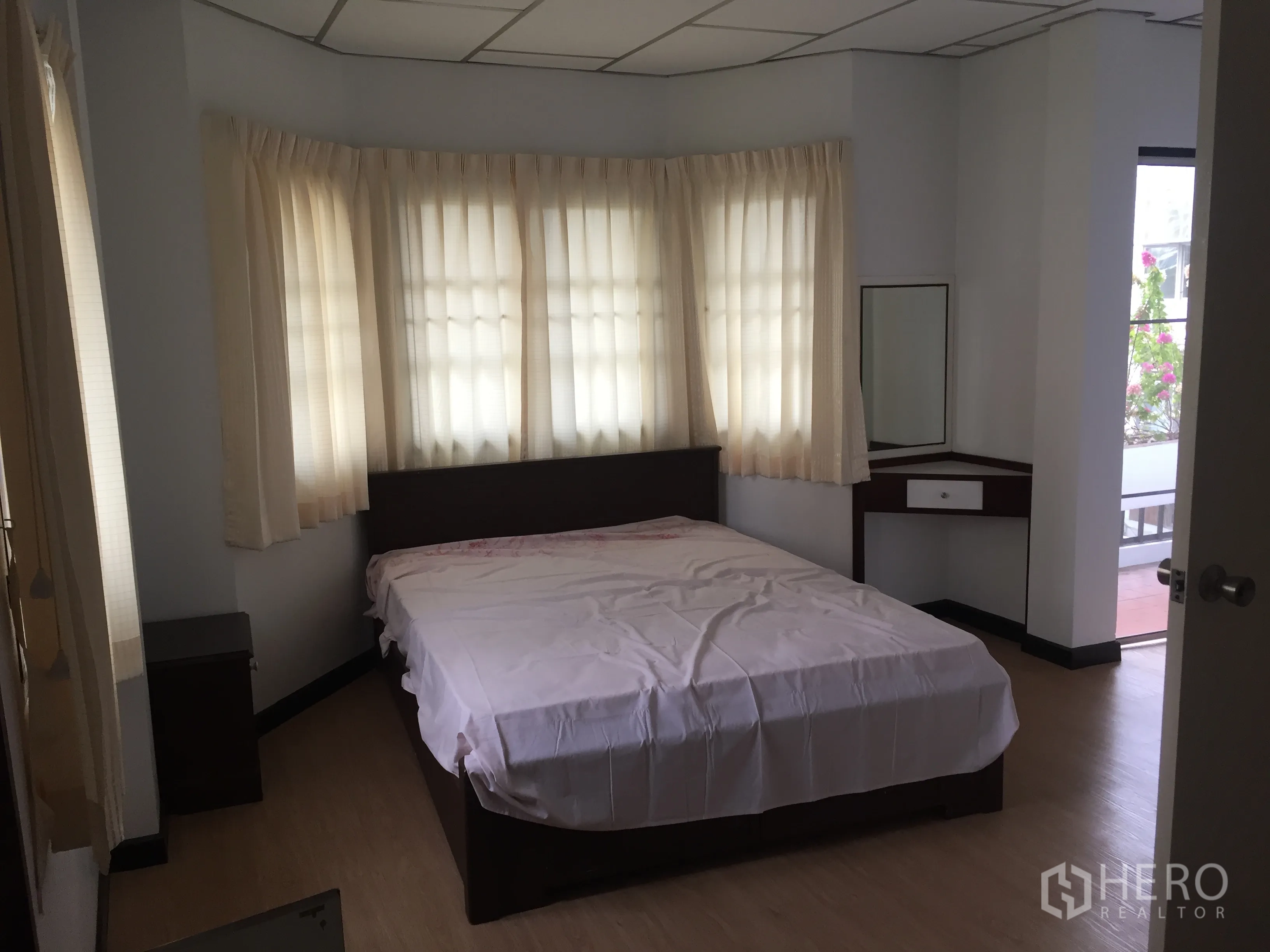 Townhouse for rent in Khlong Toei, Bangkok - Second bedroom with bay-style corner windows, bed, and access to a balcony.