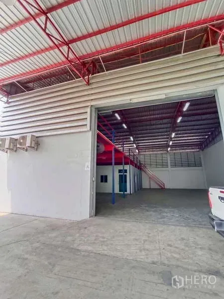 Warehouse for rent in Lat Krabang, Bangkok - Open roller door reveals a high-ceiling warehouse with mezzanine and office rooms.