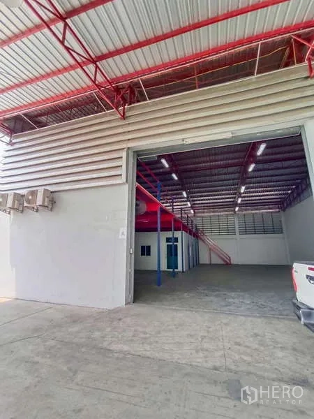 Warehouse for rent in Lat Krabang, Bangkok - Open roller door reveals a high-ceiling warehouse with mezzanine and office rooms.