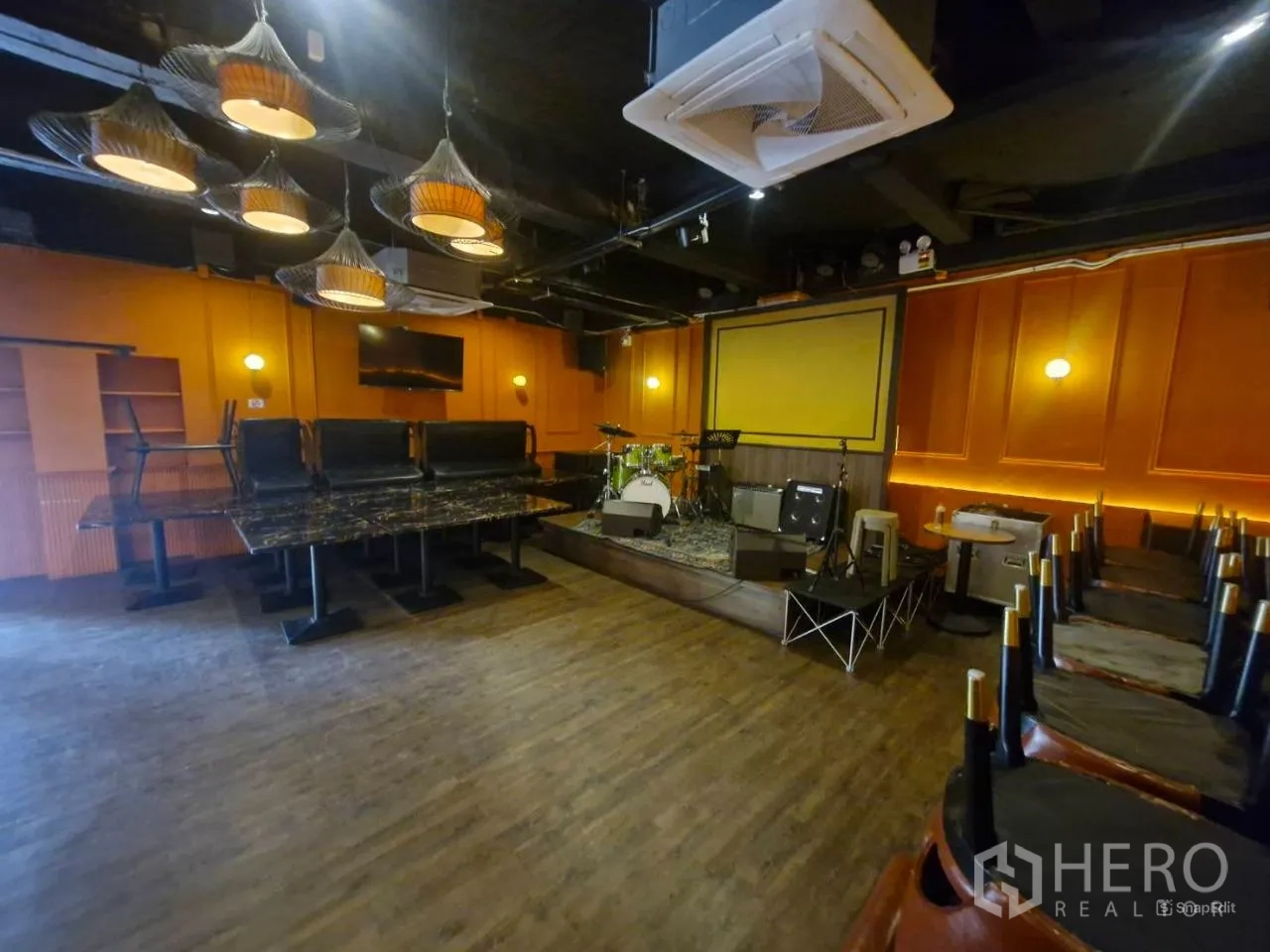 Shophouse for rent in Pathum Wan, Bangkok - Stage with drum kit, pendant lights and marble dining tables.