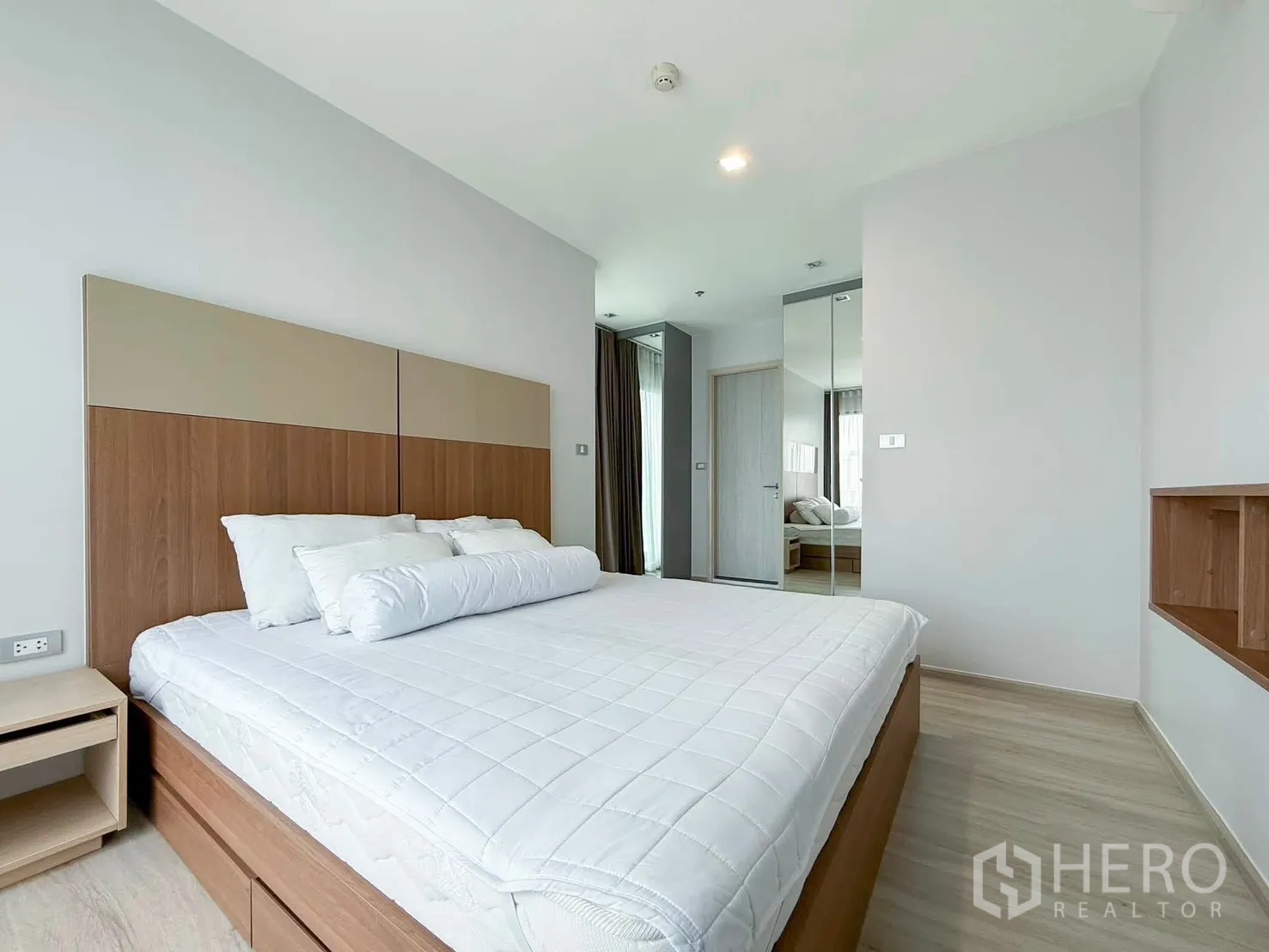 Condominium for rent in Khlong Toei, Bangkok - Spacious bedroom with padded headboard, mirrored wardrobe, and nightstands.