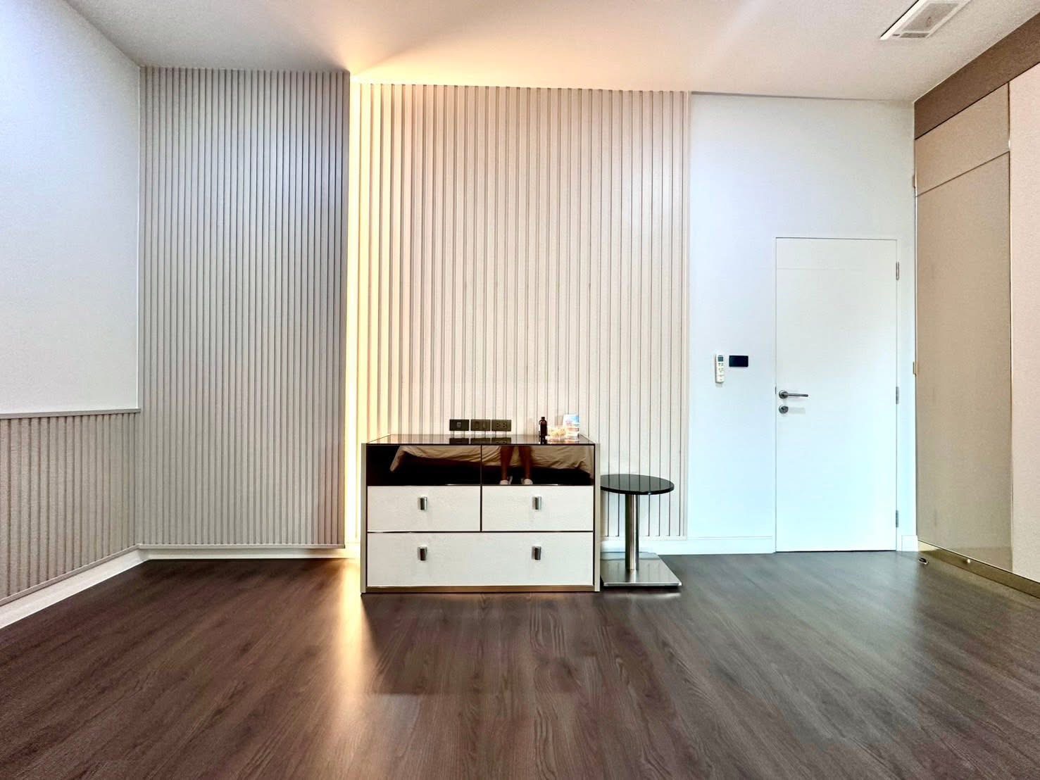 独立式住宅 出租在Bang Kapi, Bangkok - 极简角落，带斗柜、纹理墙与木地板。