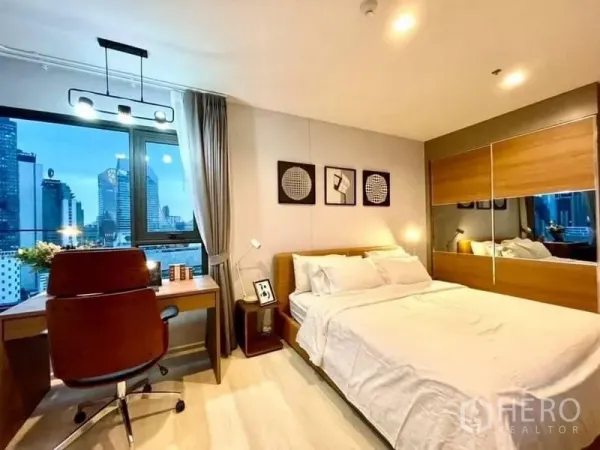 Condominium for rent in Pathum Wan, Bangkok - Second bedroom with work desk, floor-to-ceiling window and mirrored wardrobe.