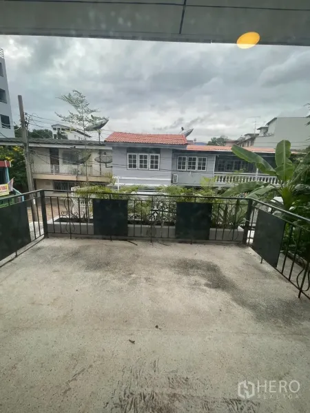 独立式住宅 出租在Watthana, Bangkok - 宽阔阳台配金属栏杆，俯瞰邻里屋舍与多云天空。