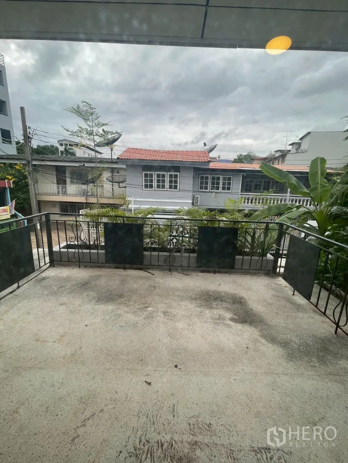 独立式住宅 出租在Watthana, Bangkok - 宽阔阳台配金属栏杆，俯瞰邻里屋舍与多云天空。